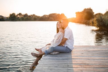 Hamile bir eşi olan bir koca, gün batımında güneşli yaz günbatımında bir rıhtımda dinleniyor. Birbirine aşık çiftler. Sarılıyorlar, el ele tutuşuyorlar.,