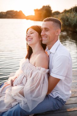 Hamile bir eşi olan bir koca, gün batımında güneşli yaz günbatımında bir rıhtımda dinleniyor. Birbirine aşık çiftler. Sarılıyorlar, el ele tutuşuyorlar.,