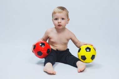 Elinde bir futbol topu tutan fanatik çocuk, beyaz bir arka planda izole edilmiş. Futbolda çaylak, çocuklar için spor. Küçük sporcu..