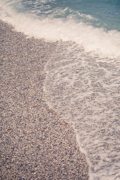 The beach of the Mediterranean coast with waves of azure water. Summer sea breeze