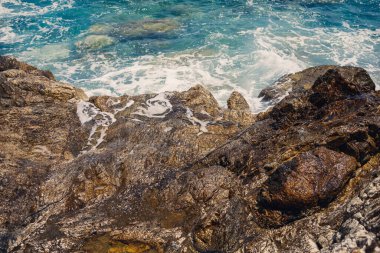 Mavi Akdeniz 'in harika manzarası. Güneşli kayalar, köpüklü dalgalar ve su sıçraması. Dalga kıyıdaki kayalara çarpar.