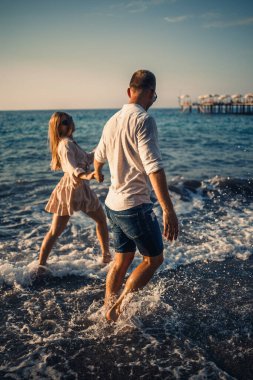 Birbirine aşık romantik genç çift Akdeniz sahilleri boyunca kumsalda yürüyor. Sıcak bir ülkede yaz tatili.