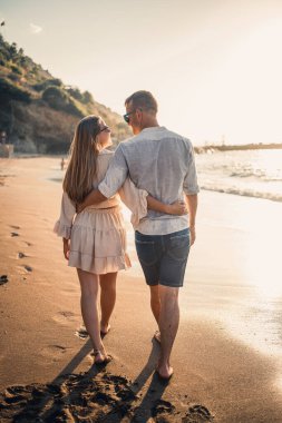 Yaz tatili ve seyahat. Gün batımında deniz suyunda seksi kadın ve erkek. Sevgili çift güneşin doğduğu kumsalda dinleniyor. Birlikte bir yaz gününün tadını çıkaran bir çiftin aşk ilişkisi.