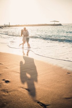 Yaz tatili ve seyahat. Gün batımında deniz suyunda seksi kadın ve erkek. Sevgili çift güneşin doğduğu kumsalda dinleniyor. Birlikte bir yaz gününün tadını çıkaran bir çiftin aşk ilişkisi. Seçici odak