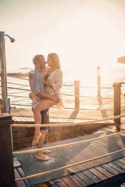 Deniz kenarında mutlu bir çift. Bir adam ve bir kız açık hava rıhtımında duşun altındalar. Tatildeki mutlu çift. Deniz kenarındaki kadın ve erkek.