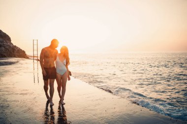 Birbirine aşık romantik genç çift gün batımında Akdeniz sahilinde birlikte yürüyor. Sıcak bir ülkede yaz tatili. Mutlu evli çift Türkiye 'de tatilde. Seçici odak