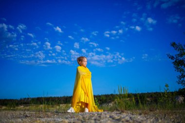 Özgürlüğün sembolü, 7 yaşında Ukraynalı bir kız. Mavi gökyüzüne karşı vatansever bir şekilde sarı bir elbise giymiş. Mavi gökyüzü. Güneşli bir gün. Özgür Ukraynalı çocuk. Ukrayna 'nın çocuk sembolü