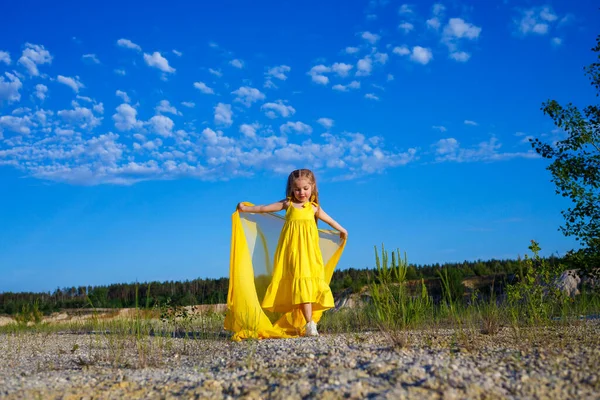 Ukraynalı 7 yaşında, Ukraynalı bir vatansever, mavi gökyüzüne karşı sarı bir elbise giymiş. Mavi gökyüzü. Güneşli bir gün. Özgür Ukraynalı çocuk. Ukrayna 'nın çocuk sembolü