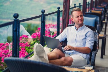 Duygusal bir adam tatilde bilgisayarın başına oturur ve çalışır. Freelancer tatildeyken çalışıyor. Yüksek kalite fotoğraf