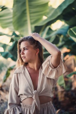 Adada yeşil muz yapraklarının yanında duran bir kadın. Tropik ağaçlar