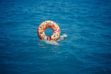 Şeffaf turkuaz denizde şişme bir çöreğin üzerinde yüzen genç bir kadın. İnce bir bayanın Türkiye, Mısır ve Akdeniz 'de tatil yaparken dinlenmesi.