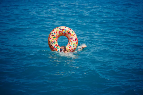 透明ターコイズブルーの海に浮かぶ膨脹可能な大きなドーナツに浮かぶ若い女性 トルコ エジプト 地中海で休暇中にリラックスした細い女性の眺め — ストック写真