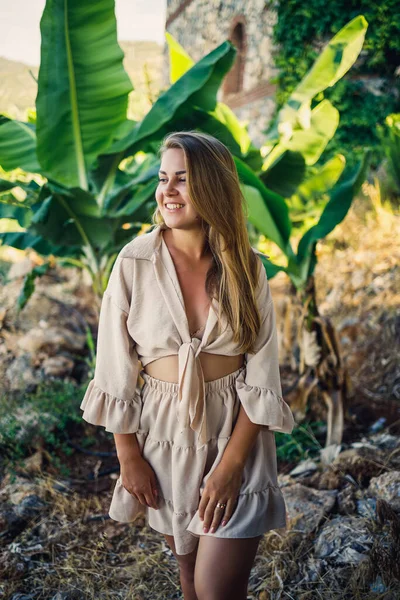 Çekici, genç, açık tenli kadın tropikal parkta muz ağaçlarının yanında duruyor..