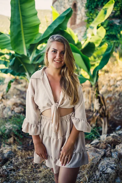 Çekici, genç, açık tenli kadın tropikal parkta muz ağaçlarının yanında duruyor..