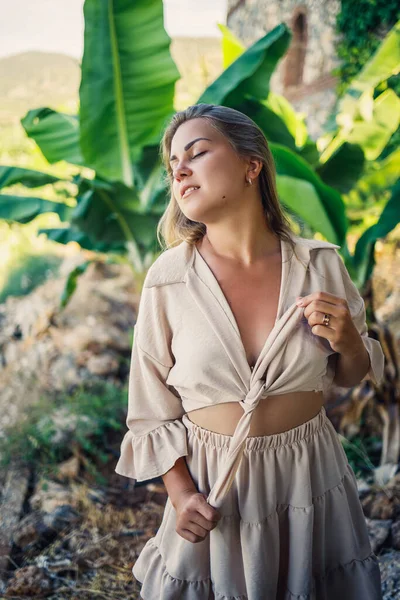Çekici, genç, açık tenli kadın tropikal parkta muz ağaçlarının yanında duruyor..