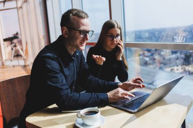 Bir iş projesinde birlikte çalışıyoruz. İki genç iş arkadaşı, modern büyük bir ofiste dizüstü bilgisayarda çalışıyor. İş yerindeki iş ortakları