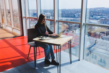 İnternette bir kafede çalışıyorum. Günlük kıyafetleri ve gözlükleriyle dizüstü bilgisayar kullanan mutlu bir kız. Şehirde rahat bir yaşam tarzı için modern dijital teknolojilerle uzaktan çalışma veya eğitim.