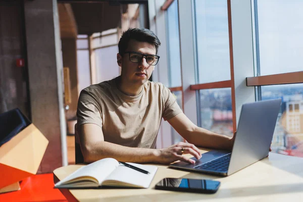 Gözlüklü, gülümseyen, zeki, genç bir serbest yazar bir kafede vakit geçirirken dizüstü bilgisayarda çalışıyor. Pozitif bir öğrenci bir kafede ahşap bir masada oturur. Mutlu adam içeride çalışırken oturuyor.