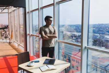 Şirketteki bir iş gününde pencerenin yanında duran başarılı bir erkek girişimci başarılı bir şirket patronu zengin bir hayat tarzından memnun olur.