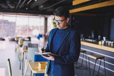 Kafede not defteriyle çalışan serbest çalışan genç bir adam, not defterli bir iş adamı, ceket ve gözlüklü bir adam.