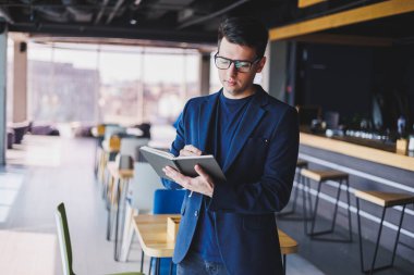 Kafede not defteriyle çalışan serbest çalışan genç bir adam, not defterli bir iş adamı, ceket ve gözlüklü bir adam.