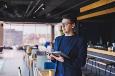 Kafede not defteriyle çalışan serbest çalışan genç bir adam, not defterli bir iş adamı, ceket ve gözlüklü bir adam.