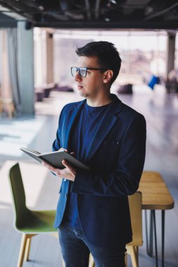 Kafede not defteriyle çalışan serbest çalışan genç bir adam, not defterli bir iş adamı, ceket ve gözlüklü bir adam.