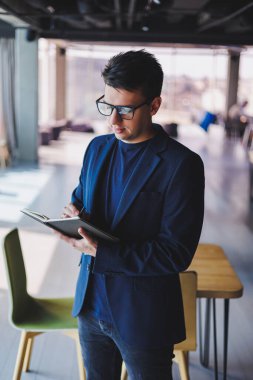 Kafede not defteriyle çalışan serbest çalışan genç bir adam, not defterli bir iş adamı, ceket ve gözlüklü bir adam.