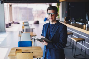 Kafede not defteriyle çalışan serbest çalışan genç bir adam, not defterli bir iş adamı, ceket ve gözlüklü bir adam.