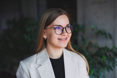 Yüzünde düzeltme gözlüğü olan güzel, sarışın bir kadının portresi.