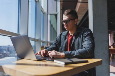 İşletme bilgisi, kurumsal para yatırım raporu, dizüstü bilgisayarlar ve dijital pazarlama üzerine çevrimiçi araştırma yaparken notlar yazan profesyonel yönetici.