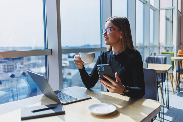 Счастливая европейская женщина работает онлайн в кафе, используя ноутбук и кофейное пространство. Успешная женщина-фрилансер, печатающая на ноутбуке, удаленная работа