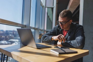 Gözlüklü bir serbest çalışan dizüstü bilgisayara bakar ve gün içinde elinde dizüstü bilgisayar ve kafede not defteri olan bir masada otururken kızar. Şanssız bir gün. Ofisten uzakta çalışıyor..