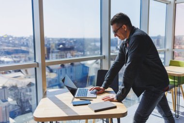 İşletme bilgisi, kurumsal para yatırım raporu, dizüstü bilgisayarlar ve dijital pazarlama üzerine çevrimiçi araştırma yaparken notlar yazan profesyonel yönetici.