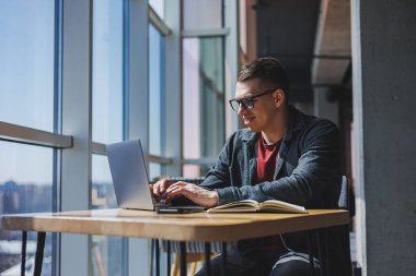 İşletme bilgisi, kurumsal para yatırım raporu, dizüstü bilgisayarlar ve dijital pazarlama üzerine çevrimiçi araştırma yaparken notlar yazan profesyonel yönetici.