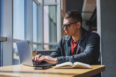 İşletme bilgisi, kurumsal para yatırım raporu, dizüstü bilgisayarlar ve dijital pazarlama üzerine çevrimiçi araştırma yaparken notlar yazan profesyonel yönetici.