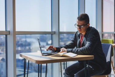İşletme bilgisi, kurumsal para yatırım raporu, dizüstü bilgisayarlar ve dijital pazarlama üzerine çevrimiçi araştırma yaparken notlar yazan profesyonel yönetici.
