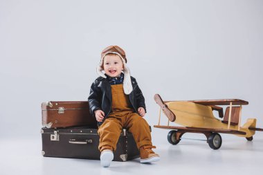 Kasklı ve pilot ceketli mutlu bir çocuk ahşap bir uçağın yanında duruyor. Bir çocuk pilotun portresi, deri ceketli bir çocuk. Tahta oyuncaklar. Ağaçtan eko düzlem