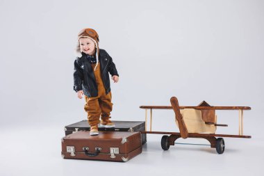 Kasklı ve pilot ceketli mutlu bir çocuk ahşap bir uçağın yanında duruyor. Bir çocuk pilotun portresi, deri ceketli bir çocuk. Tahta oyuncaklar. Ağaçtan eko düzlem