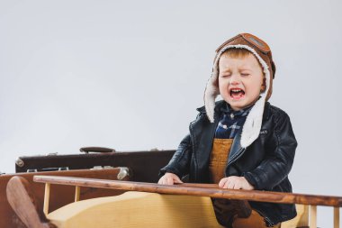 Çocuk deri bir ceket ve pilot şapkası içinde ağlıyordu. Tahta bir uçak, kahverengi bavullar. Çocukların tahta oyuncakları. Bebek duyguları