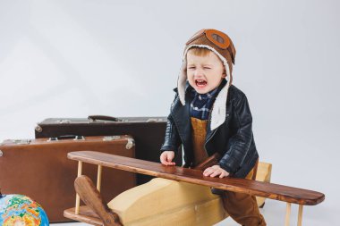 Çocuk deri bir ceket ve pilot şapkası içinde ağlıyordu. Tahta bir uçak, kahverengi bavullar. Çocukların tahta oyuncakları. Bebek duyguları