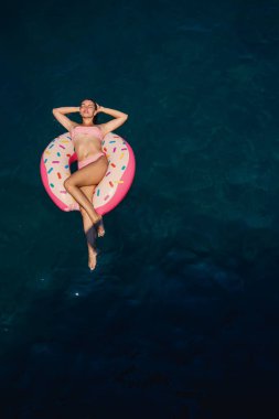 Mayolu genç bir kadın denizde şişme bir yüzükte yüzüyor. Yaz tatili kavramı.
