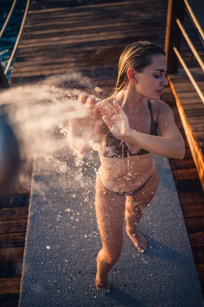 Güzel genç bir kadın açık denizde güneşli bir günde mayoyla rahatlatıcı bir duş alır. Tatildeki kız dinleniyor. Seçici odak