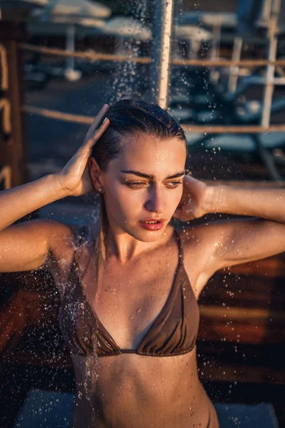 美しい若い女性が海によって夕日の光の中でシャワーで完璧な図と水着で 休暇でゴールデンタンと女の子 — ストック写真