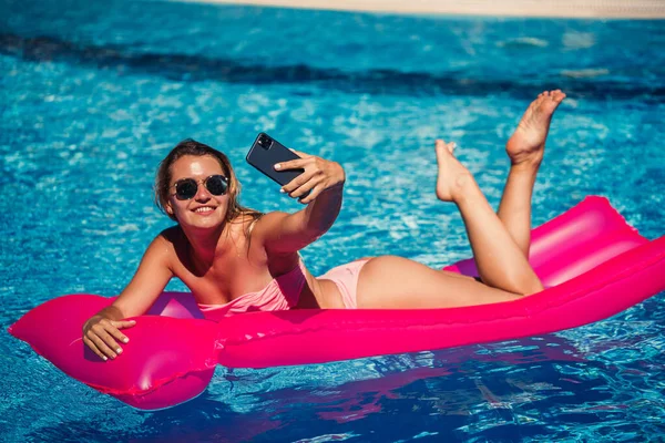 Seksowna Kobieta Telefonem Stroju Kąpielowym Leży Różowym Dmuchanym Materacu Basenie — Zdjęcie stockowe