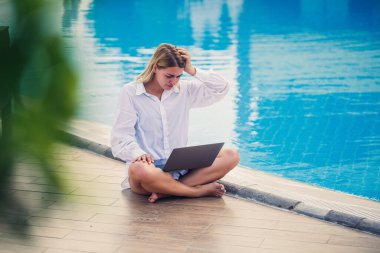 Havuz başında dizüstü bilgisayarla çalışan güzel bir kadın. Serbest uzaktan çalışma