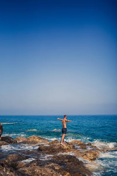 Ένας Νεαρός Άνδρας Στέκεται Στους Βράχους Θέα Την Ανοιχτή Μεσόγειο — Φωτογραφία Αρχείου