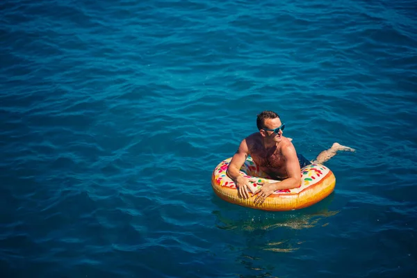 Νεαρός Άνδρας Ένα Φουσκωτό Δαχτυλίδι Στη Θάλασσα Ξεκουράζεται Και Κολυμπάει — Φωτογραφία Αρχείου