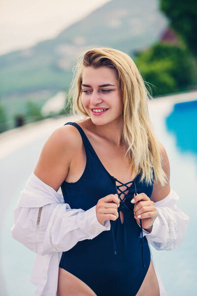 Portrait of an attractive young woman with blond hair in a black swimsuit and white shirt