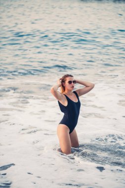 Genç ve güzel bir kadın sahilde esintinin tadını çıkarıyor. Denizde rahatlayan tasasız bir kızın portresi. Güzel, gülümseyen kadın sahilde güneşin tadını çıkarıyor..